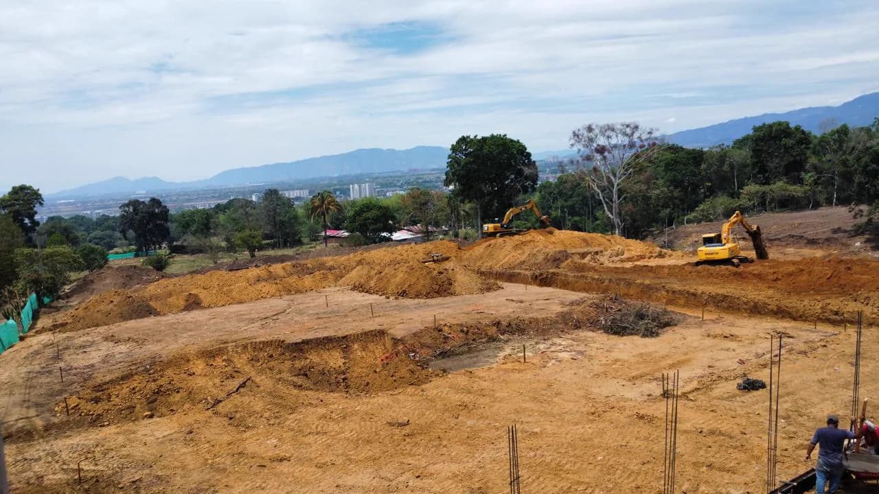 Excavadoras nivelando el terreno, con vista panorámica de Ibagué al fondo.